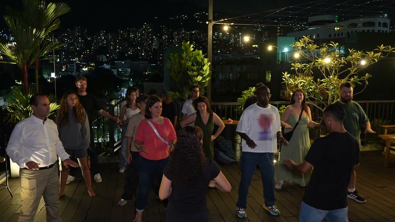 Guests dancing together on a rooftop overlooking the Medellín skyline at night